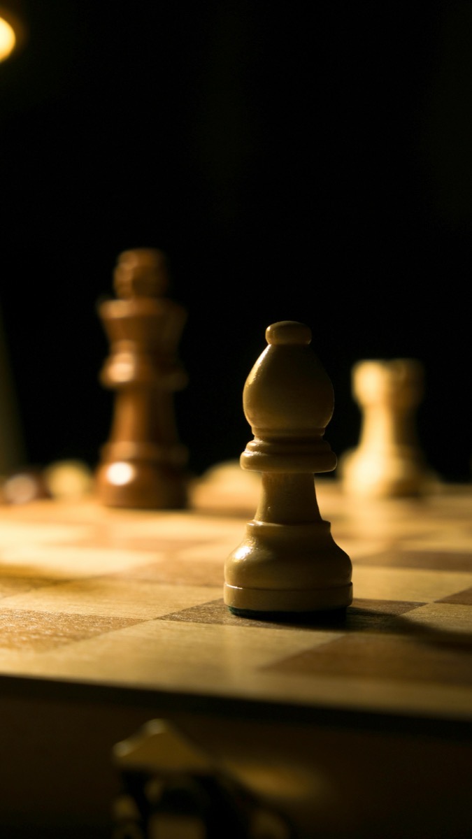 Chess pieces in low light symbolizing strategic critique