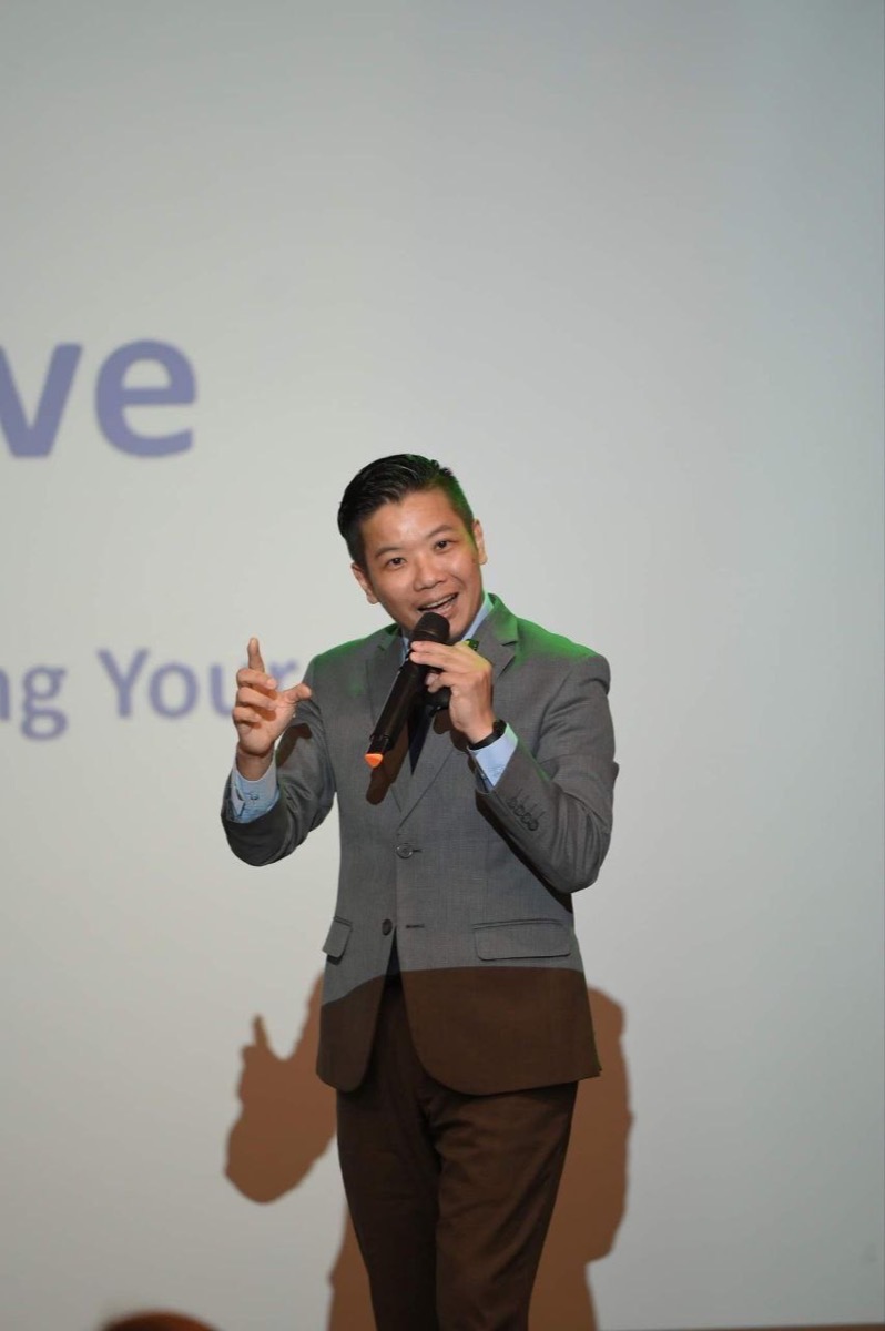 Mikael Chew gesturing on stage